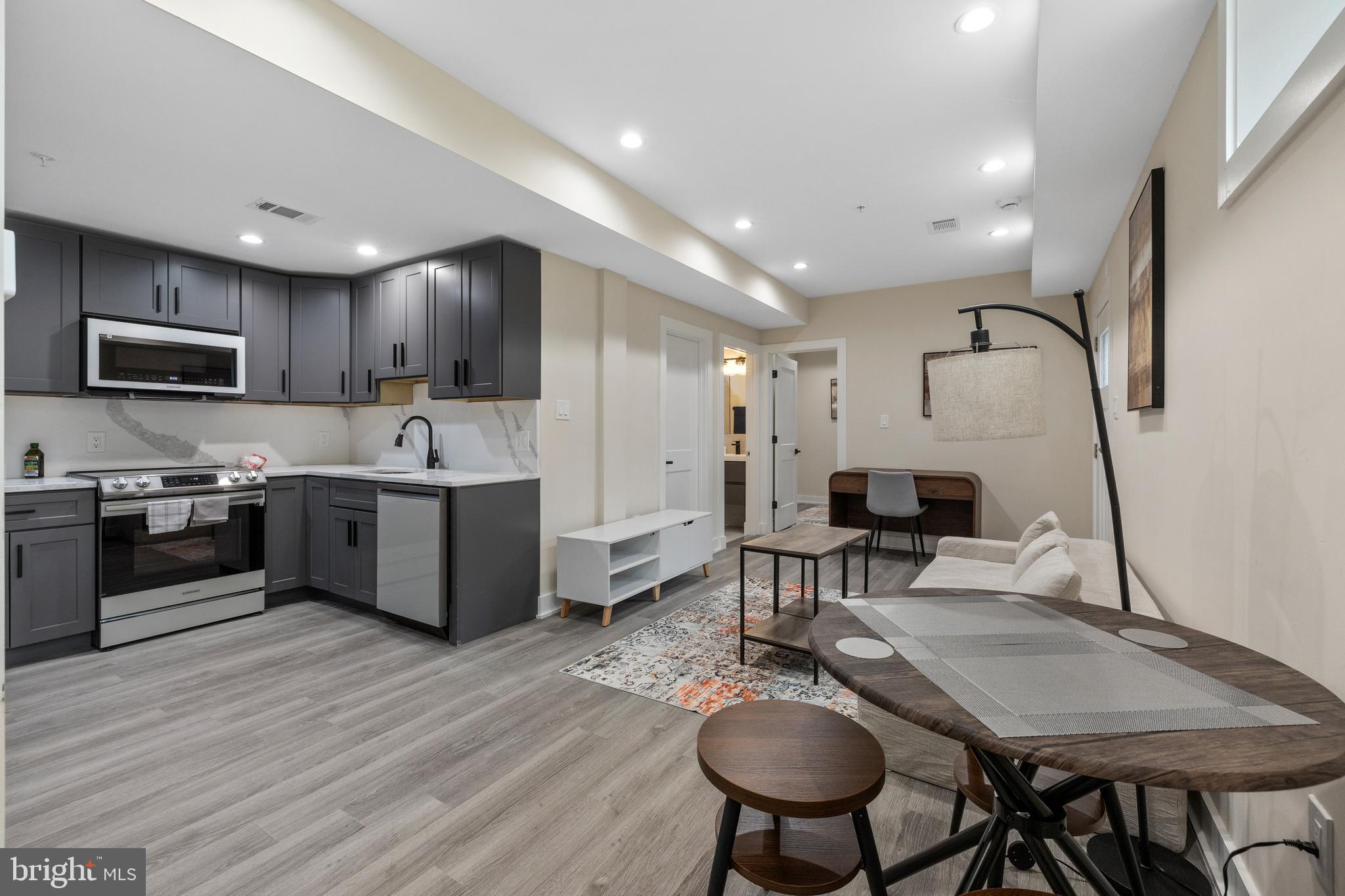 a kitchen with stainless steel appliances granite countertop a stove top oven a sink dishwasher a dining table and chairs with wooden floor