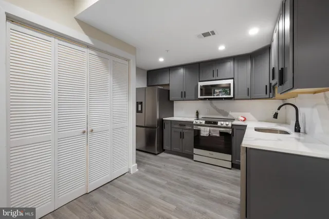 a kitchen with stainless steel appliances kitchen island granite countertop a refrigerator sink and wooden cabinets