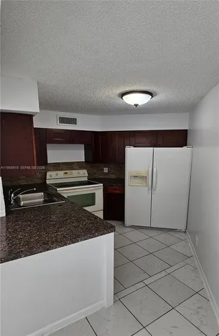 a kitchen with stainless steel appliances granite countertop a refrigerator a stove and a sink with granite countertops