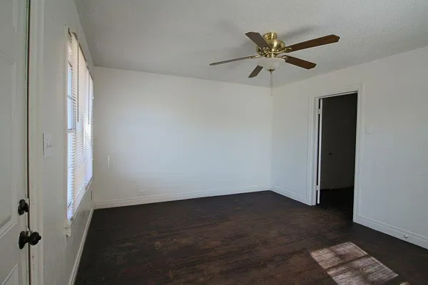 an empty room with wooden floor closet and windows