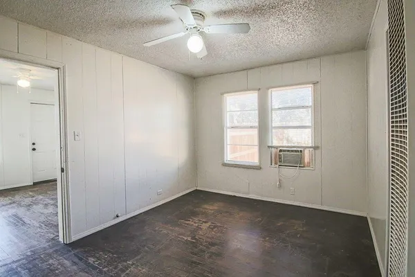 an empty room with windows and fan