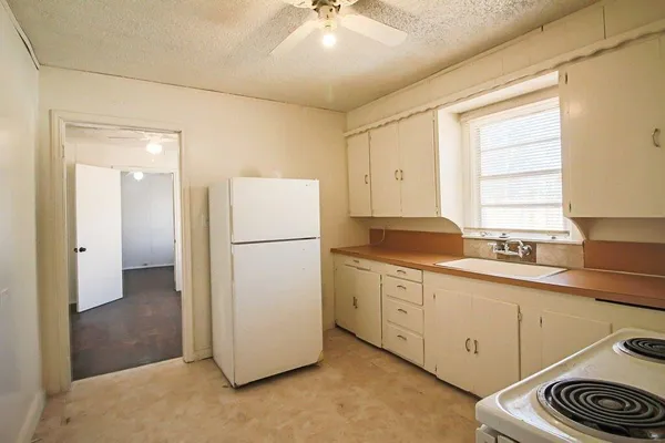a kitchen with sink a refrigerator and white cabinets