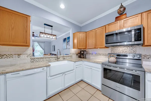 a kitchen with stainless steel appliances granite countertop grey cabinets a stove a sink and dishwasher