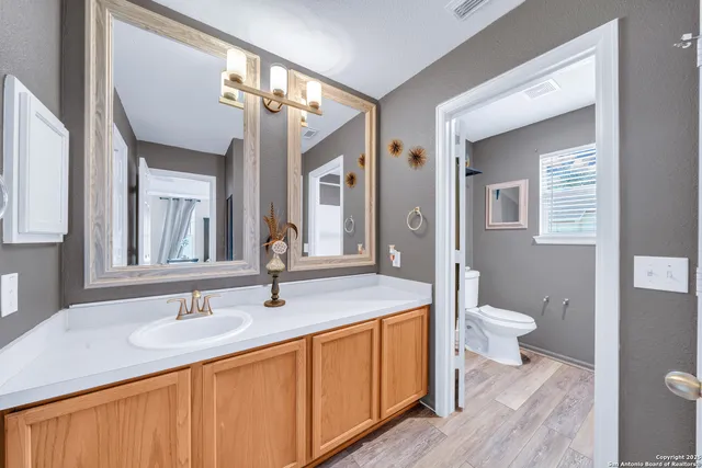 a bathroom with a granite countertop sink a toilet and a mirror