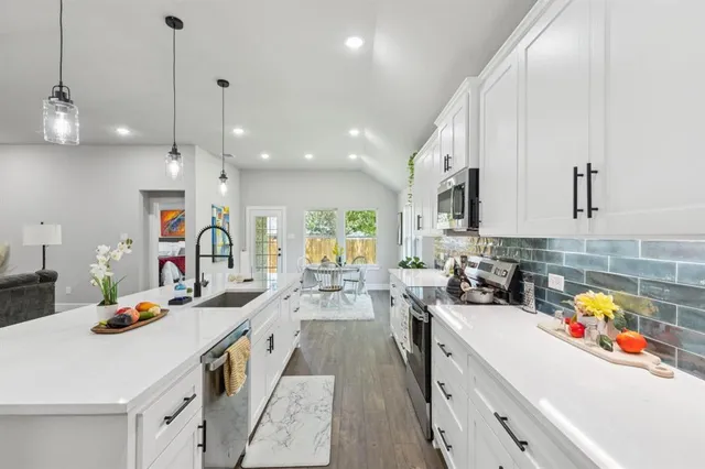 a kitchen that has a lot of cabinets a sink and appliances in it