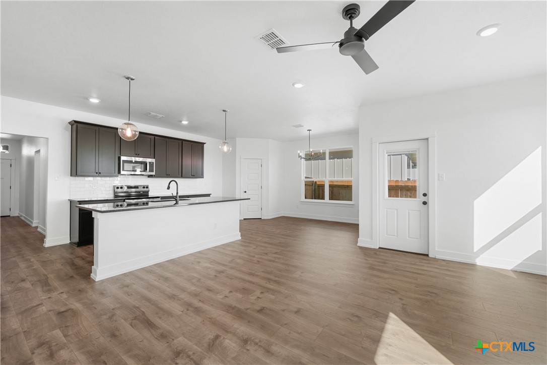 1803 Bear Grass Rdg Road Temple, TX 76501 - Photo 2 of 16 a large kitchen with kitchen island a stove a sink a refrigerator and white cabinets with wooden floor