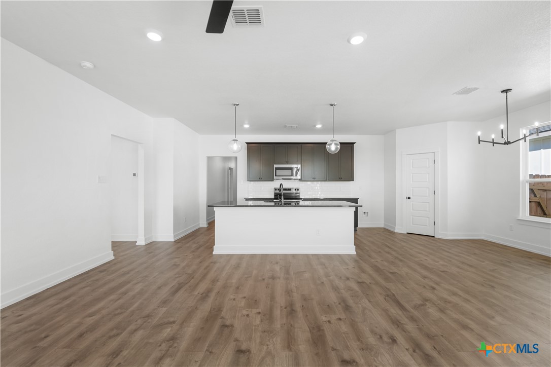 1803 Bear Grass Rdg Road Temple, TX 76501 - Photo 3 of 16 a large kitchen with stainless steel appliances a large counter top a wooden floor a fireplace and a window