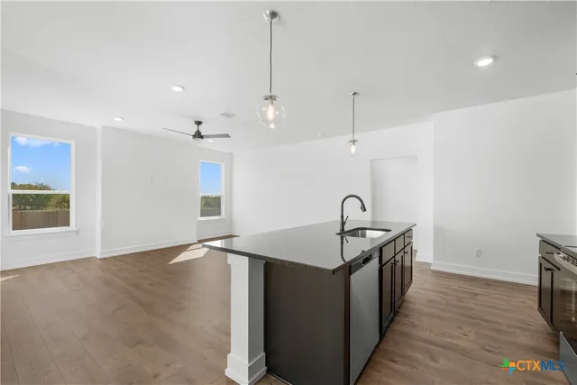 a kitchen with stainless steel appliances granite countertop a sink a stove and a wooden floor