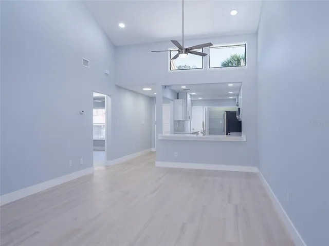 an empty room with wooden floor and a ceiling fan