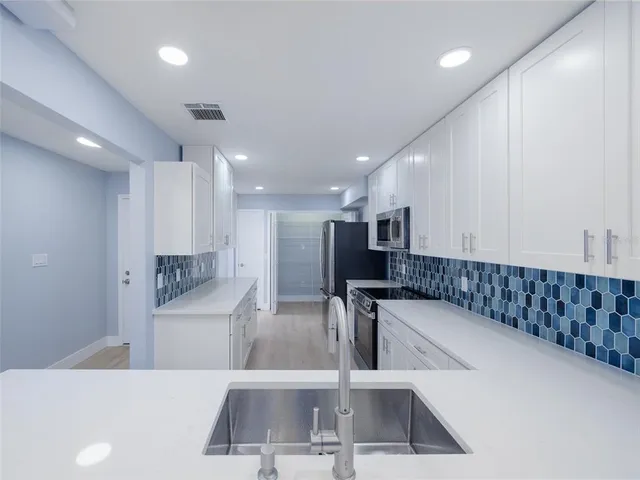 a kitchen with white cabinets appliances and sink
