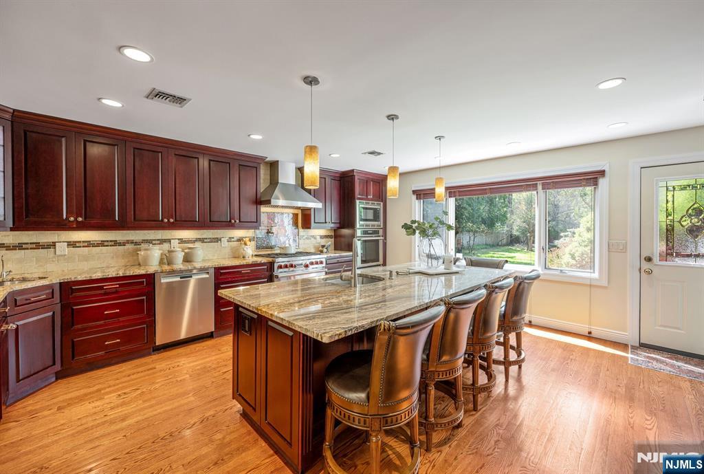 84 Bogerts Mill Road Harrington Park, NJ 07640 - Photo 9 of 47 a kitchen with kitchen island granite countertop wooden floors wooden cabinets a center island and stainless steel appliances