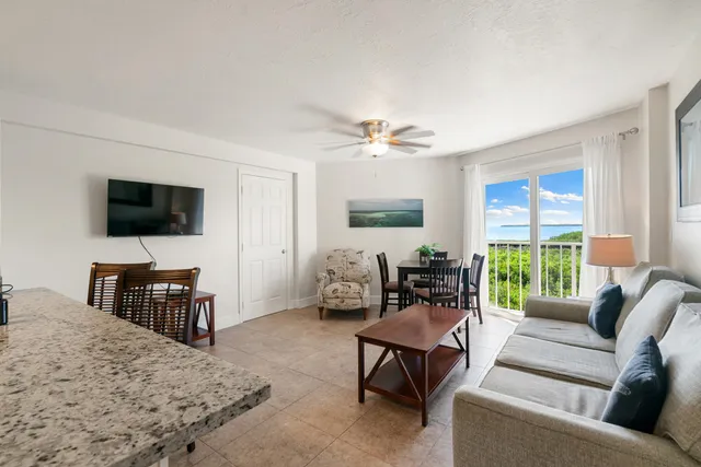 a living room with furniture kitchen view and a flat screen tv