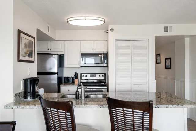 a kitchen with granite countertop a sink and a refrigerator