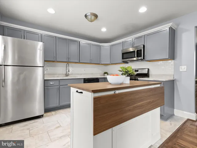 a kitchen with kitchen island granite countertop wooden floors and white cabinets