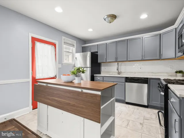 a kitchen with stainless steel appliances granite countertop a refrigerator a stove a sink a microwave a refrigerator and white cabinets with wooden floor