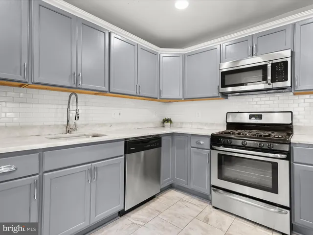 a kitchen with kitchen island granite countertop a sink cabinets and stainless steel appliances