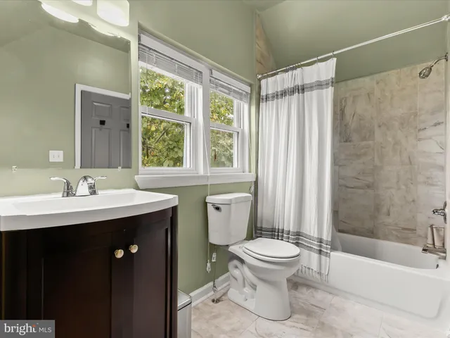 a view of a hallway with wooden floor and a bathroom