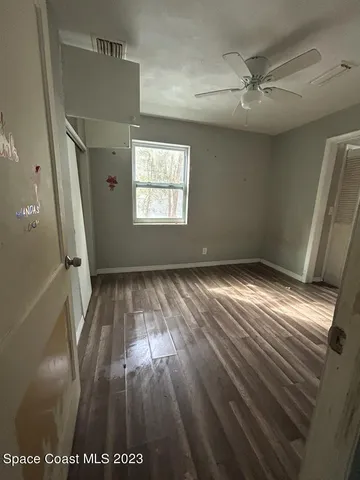 a view of empty room with wooden floor and fan
