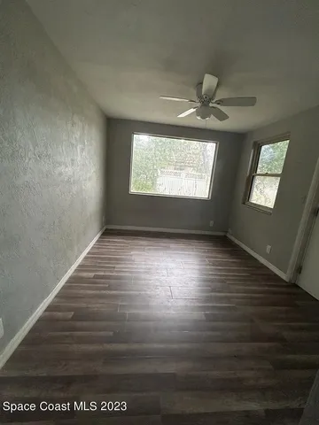 a view of empty room with wooden floor and fan