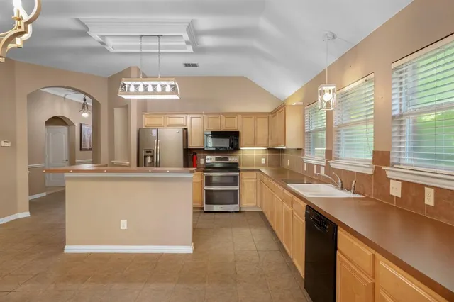a large kitchen with stainless steel appliances granite countertop a lot of counter space and a window