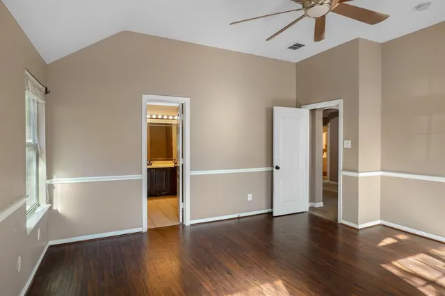a view of an empty room with a window and wooden floor
