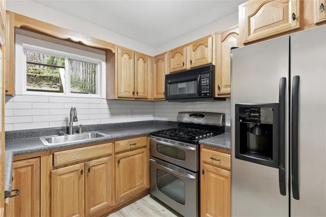 a kitchen with stainless steel appliances granite countertop a stove a sink and a microwave
