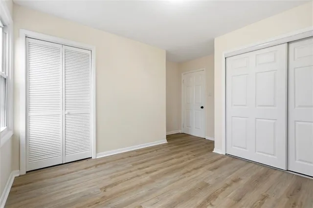 an empty room with wooden floor & closet area
