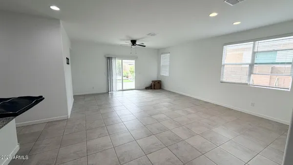 an empty room with windows and chandelier fan