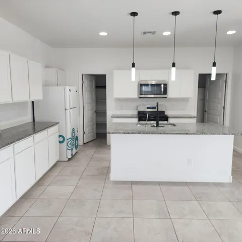 a large kitchen with stainless steel appliances kitchen island granite countertop a refrigerator a oven and a sink