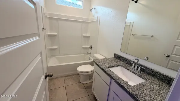 a bathroom with a granite countertop sink toilet mirror and bathtub