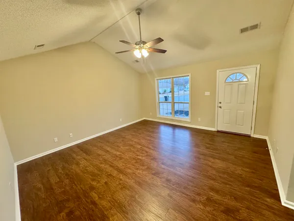 a view of an empty room with window and wooden floor