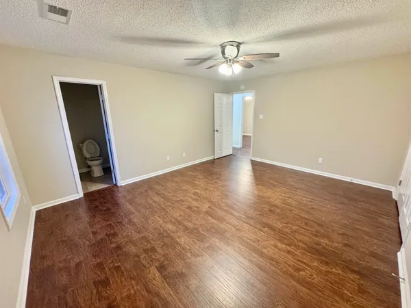 an empty room with wooden floor chandelier fan and windows