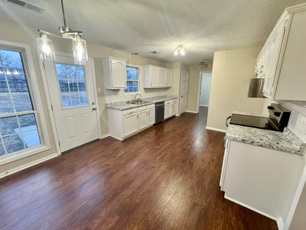 a large kitchen with lot of counter space and wooden floor