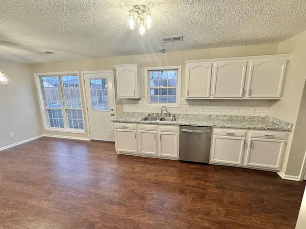 a kitchen with stainless steel appliances granite countertop a stove a sink and white cabinets