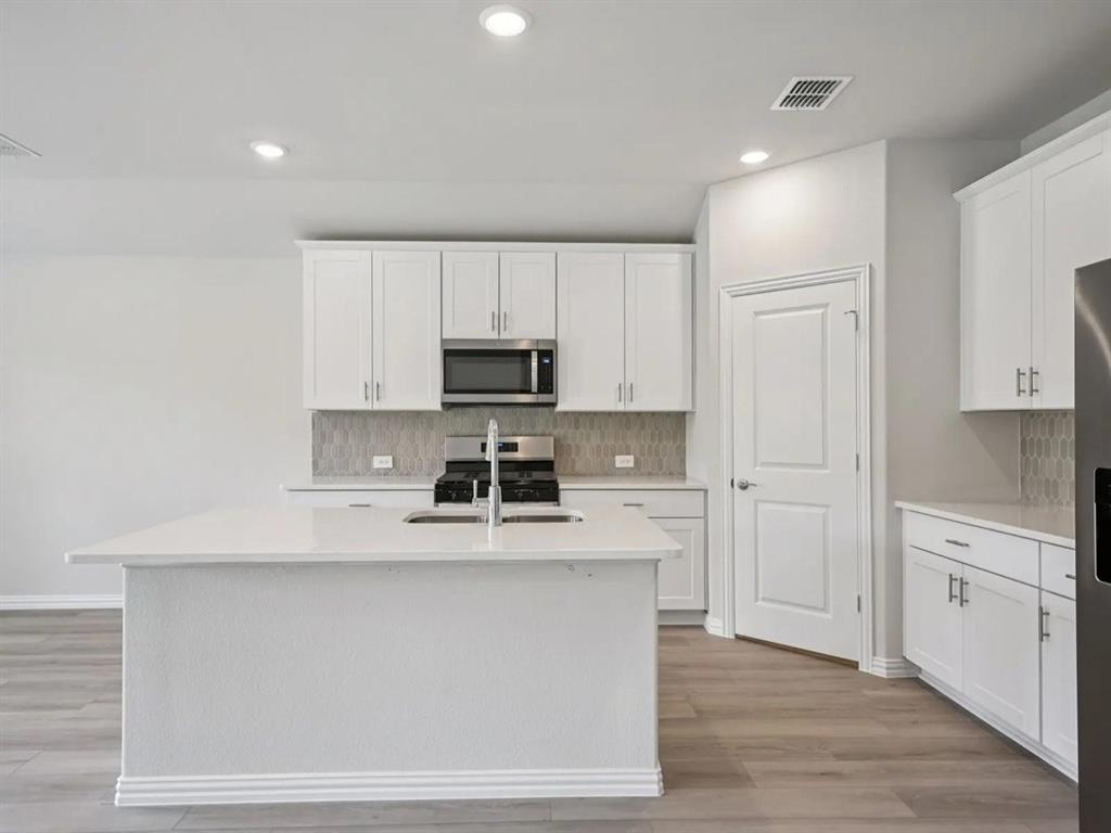 6400 Texas Ranger Trail Fort Worth, TX 76123 - Photo 10 of 14 a kitchen with kitchen island white cabinets and stainless steel appliances