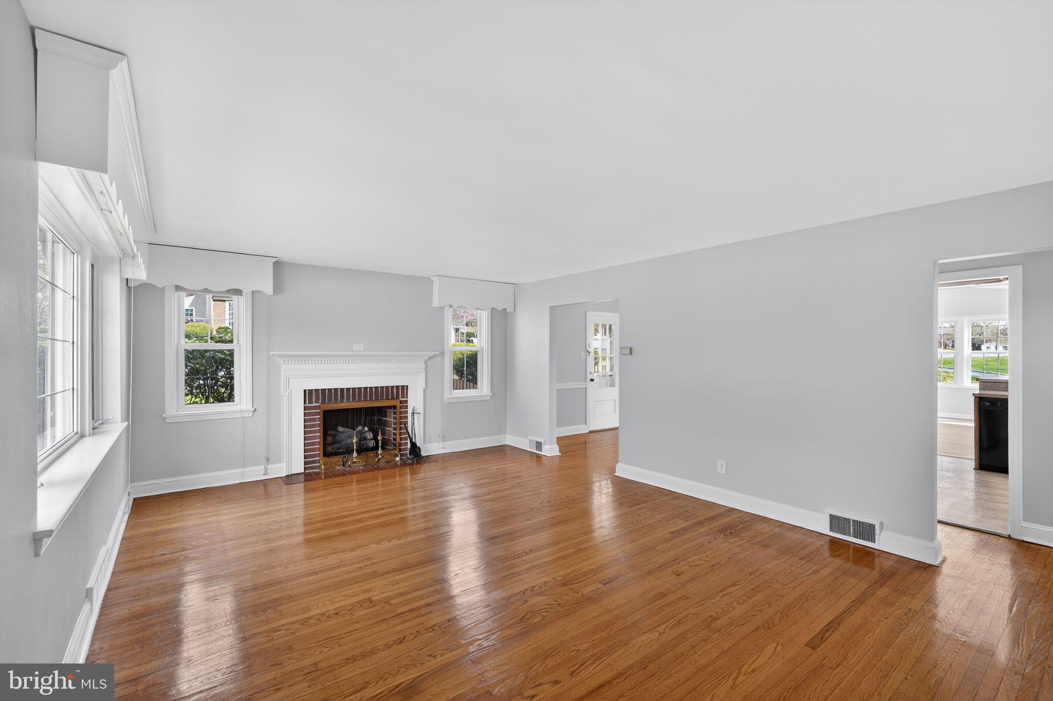 517 Weymouth Road Springfield, PA 19064 - Photo 3 of 31 an empty room with wooden floor fireplace and windows