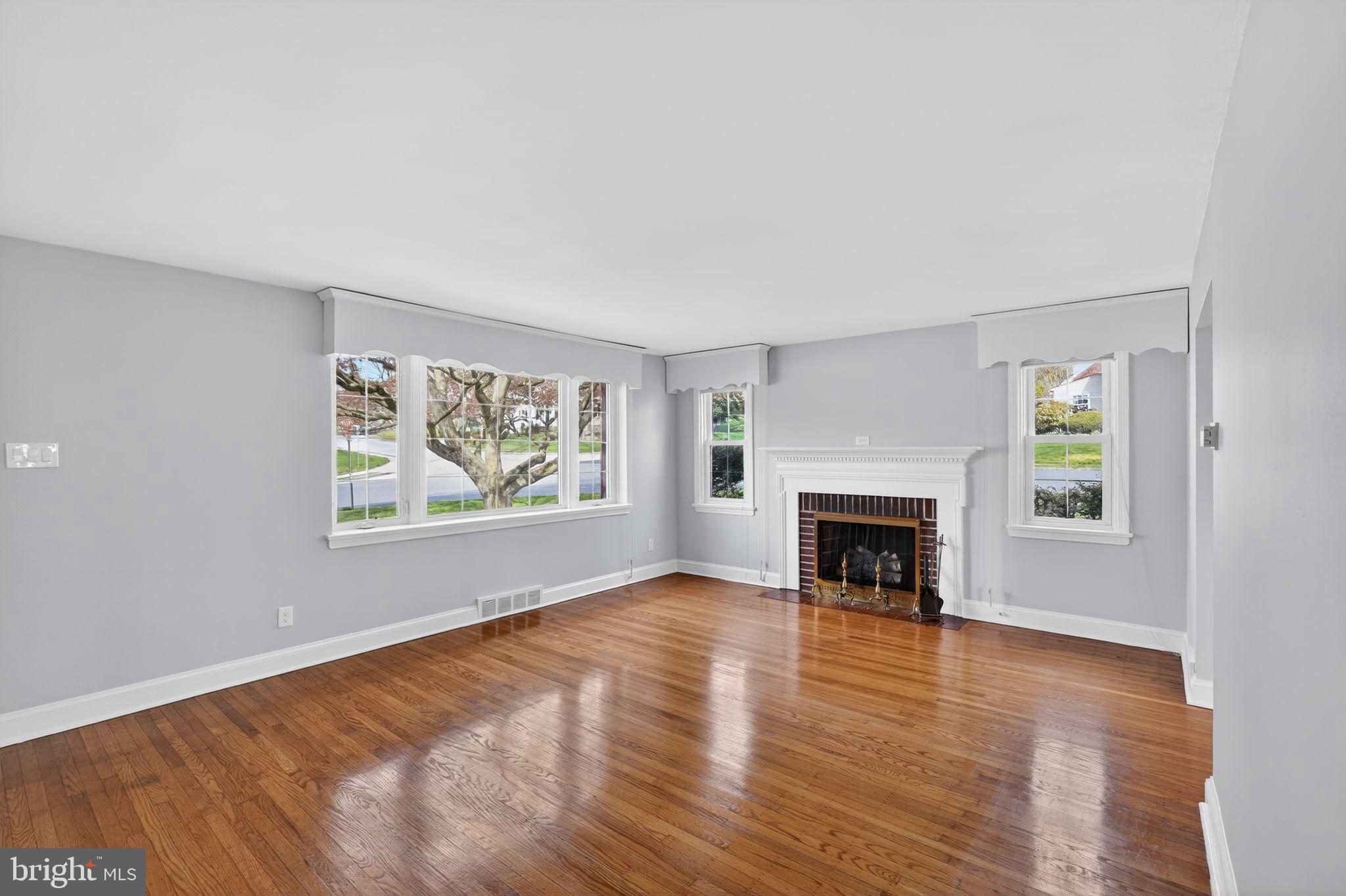 517 Weymouth Road Springfield, PA 19064 - Photo 6 of 31 an empty room with windows a fireplace and wooden floor