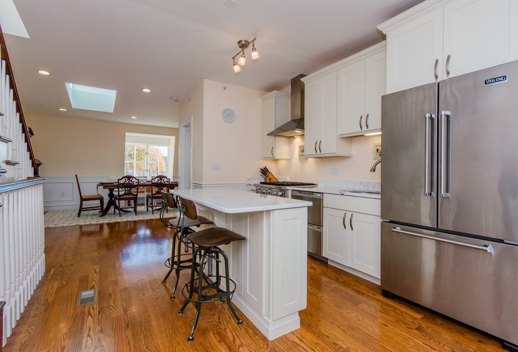 123 Warren Avenue, Unit 2 Boston, MA 02116 - Photo 2 of 13 a kitchen with stainless steel appliances a refrigerator a sink dishwasher a stove and a dining table with wooden floor