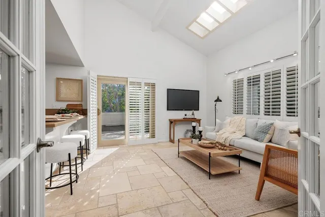 a living room with furniture a flat screen tv and a floor to ceiling window