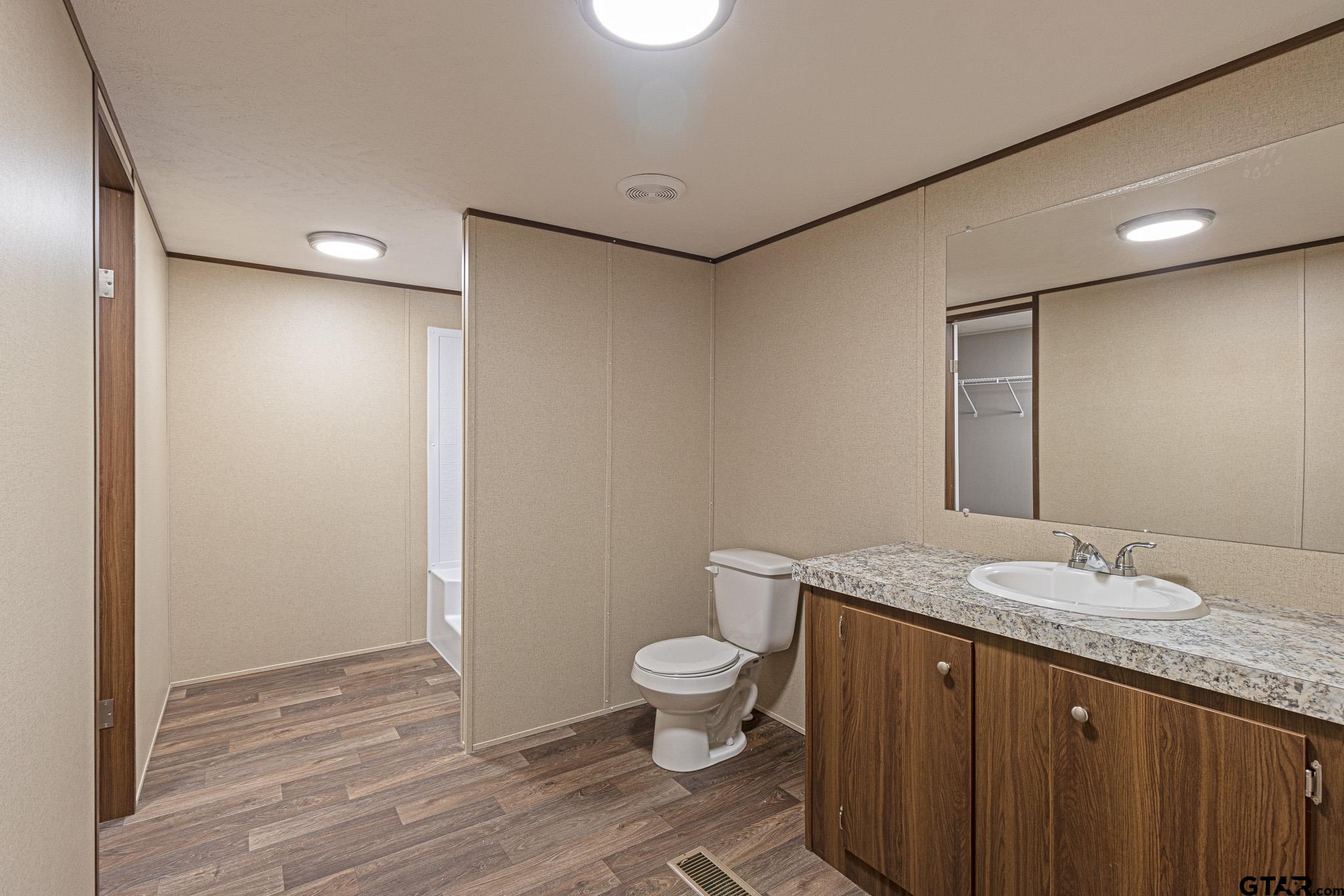 9806 FM 773 Murchison, TX 75778 - Photo 17 of 35 a bathroom with a granite countertop sink a toilet and shower