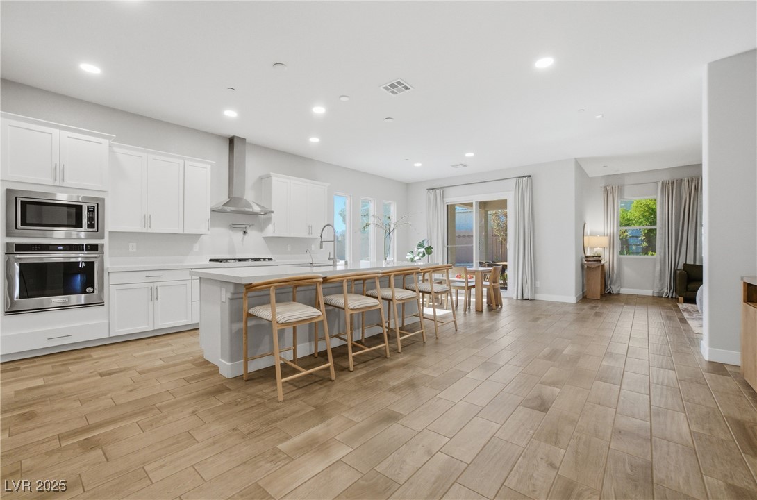 7736 Tioga Ridge Las Vegas, NV 89117 - Photo 4 of 68 Kitchen featuring stainless steel appliances, white cabinetry, a kitchen bar, an island with sink, and recessed lighting
