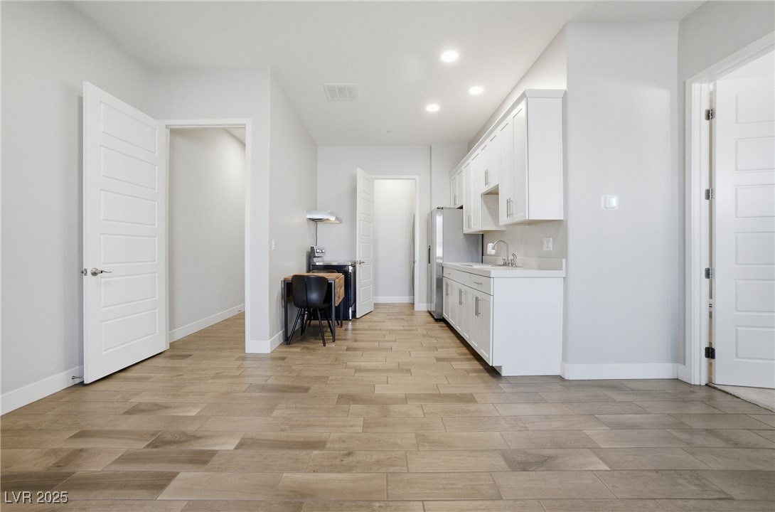 7736 Tioga Ridge Las Vegas, NV 89117 - Photo 46 of 68 Kitchen with white cabinetry, light countertops, light wood finished floors, recessed lighting, and freestanding refrigerator