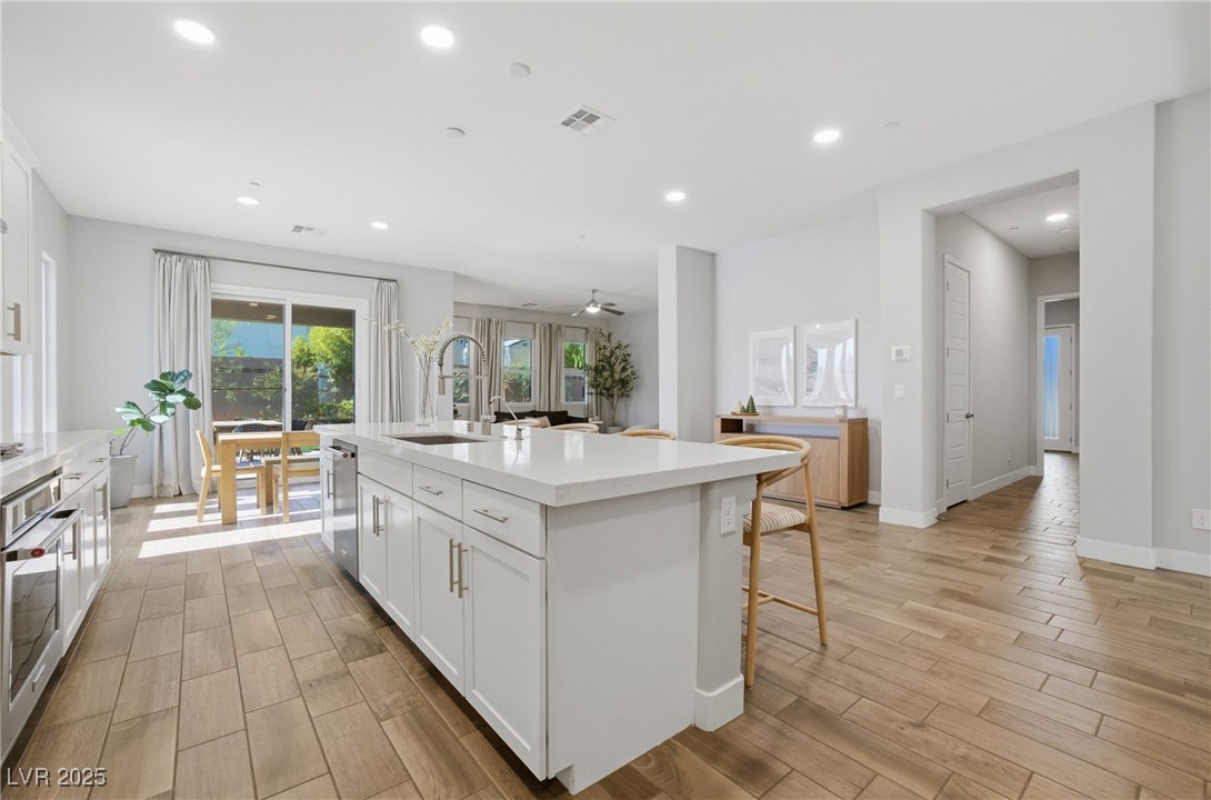 7736 Tioga Ridge Las Vegas, NV 89117 - Photo 5 of 68 Kitchen with white cabinetry, wood tiled floors, recessed lighting, stainless steel appliances, and a center island with sink