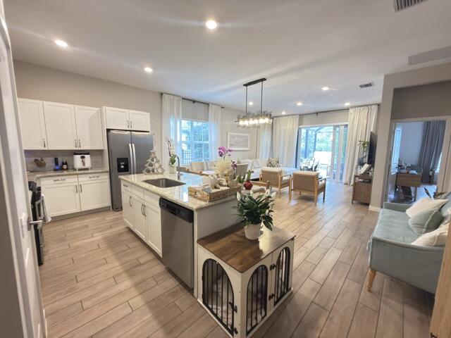 19696 Weathervane Way Loxahatchee, FL 33470 - Photo 5 of 39 a kitchen with stainless steel appliances granite countertop a stove top oven a refrigerator a sink and white cabinets with wooden floor