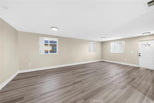 a view of an empty room with wooden floor and a window