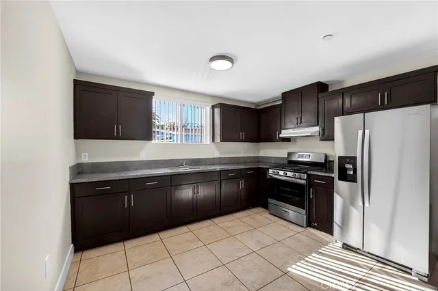 a kitchen with granite countertop a refrigerator and a stove top oven