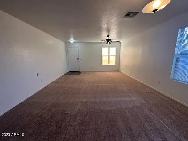 an empty room with windows and ceiling fan