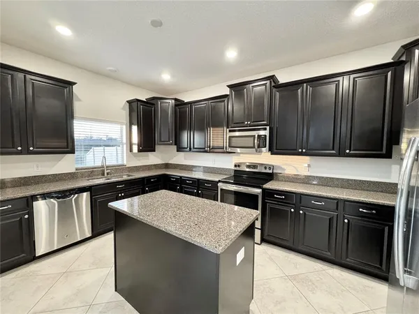 a kitchen with stainless steel appliances granite countertop a stove a sink dishwasher a refrigerator and a microwave