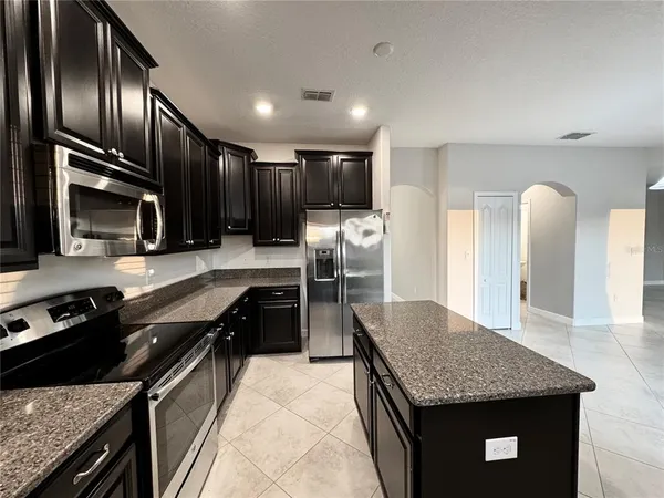 a kitchen with stainless steel appliances granite countertop a sink dishwasher stove and refrigerator