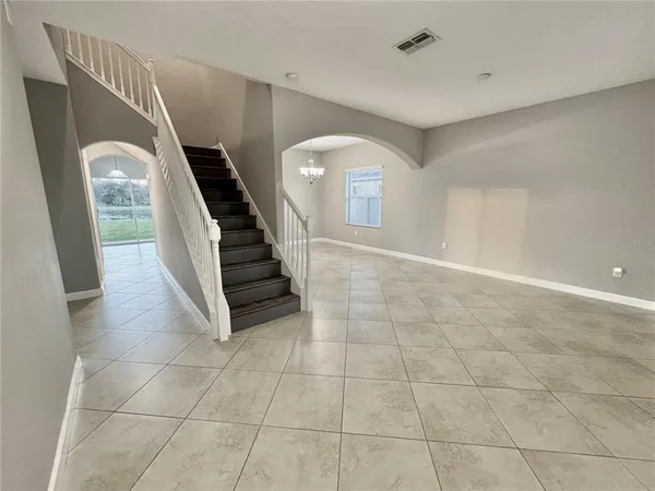 a view of a livingroom with stairs and an empty room